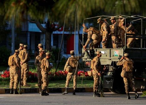 Just over a dozen Pakistani soldiers climbing out of a military vehicle.